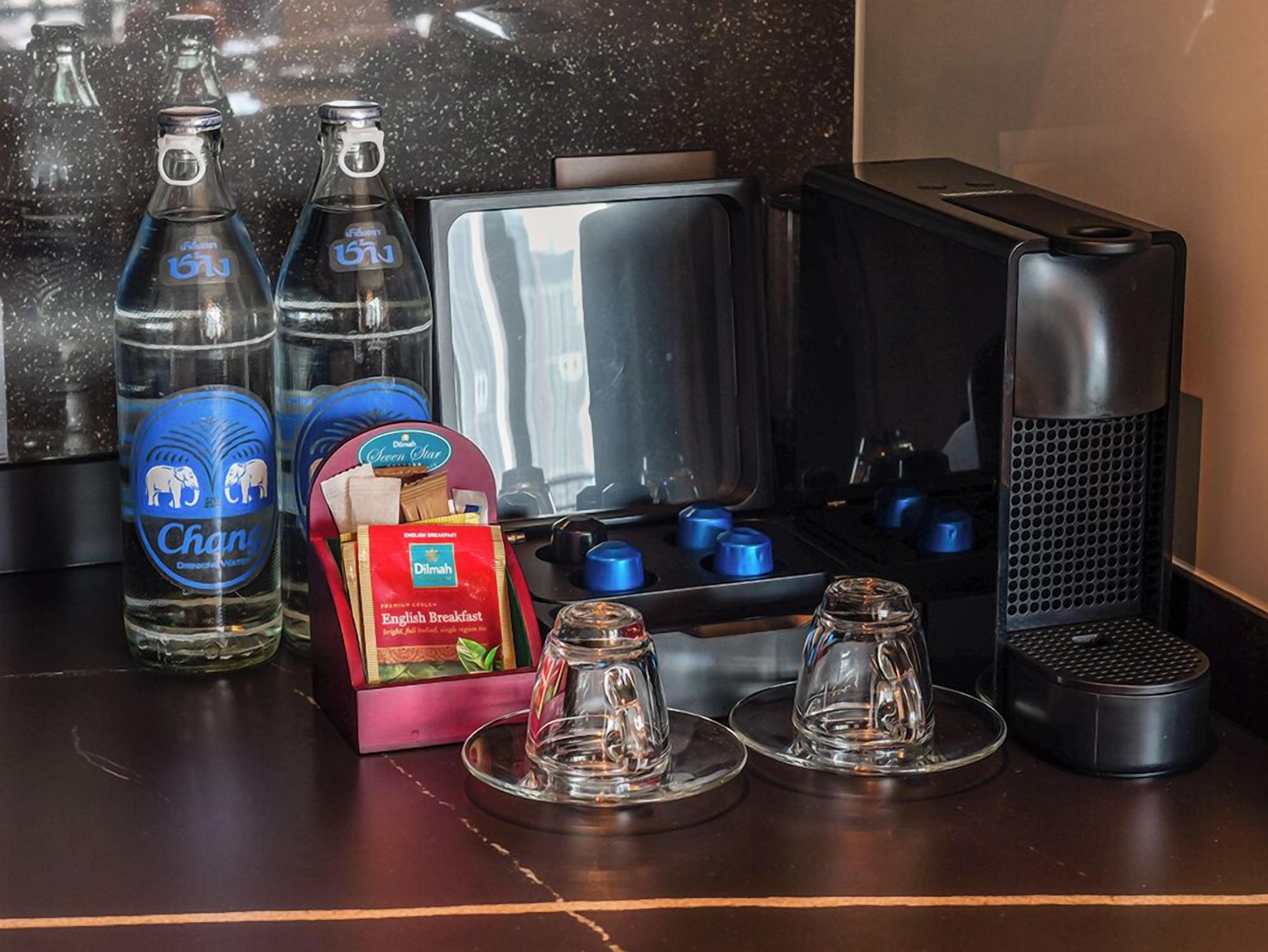 A kitchen counter with a coffee maker, two glass bottles, a box of English breakfast tea, and a microwave.