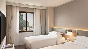 Habitación de hotel con dos camas, televisión y ventana con cortinas.