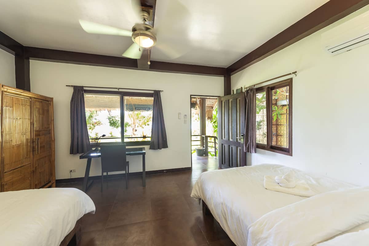 Une chambre avec deux lits, un bureau et un ventilateur de plafond.
