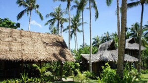 A tropical resort with thatched-roof huts, lush greenery, and palm trees.
