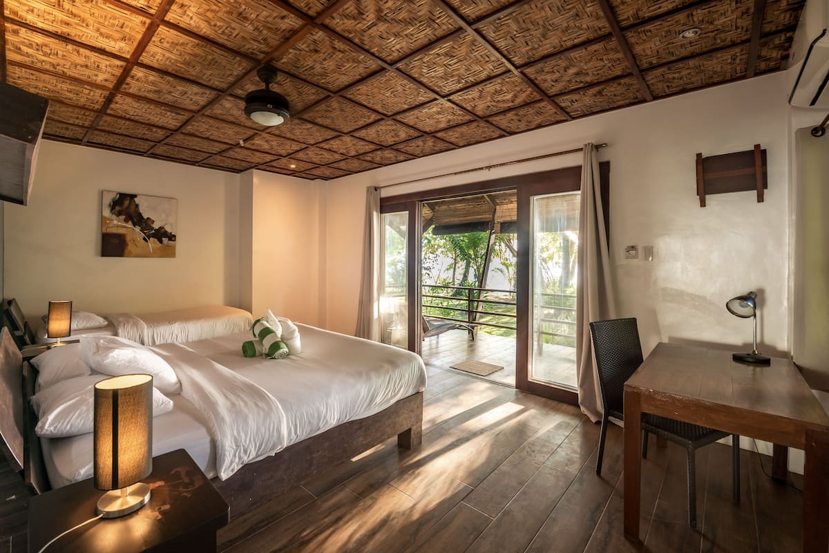 Une chambre avec un grand lit, une table en bois, une chaise et une vue sur l’extérieur grâce à une porte coulissante.