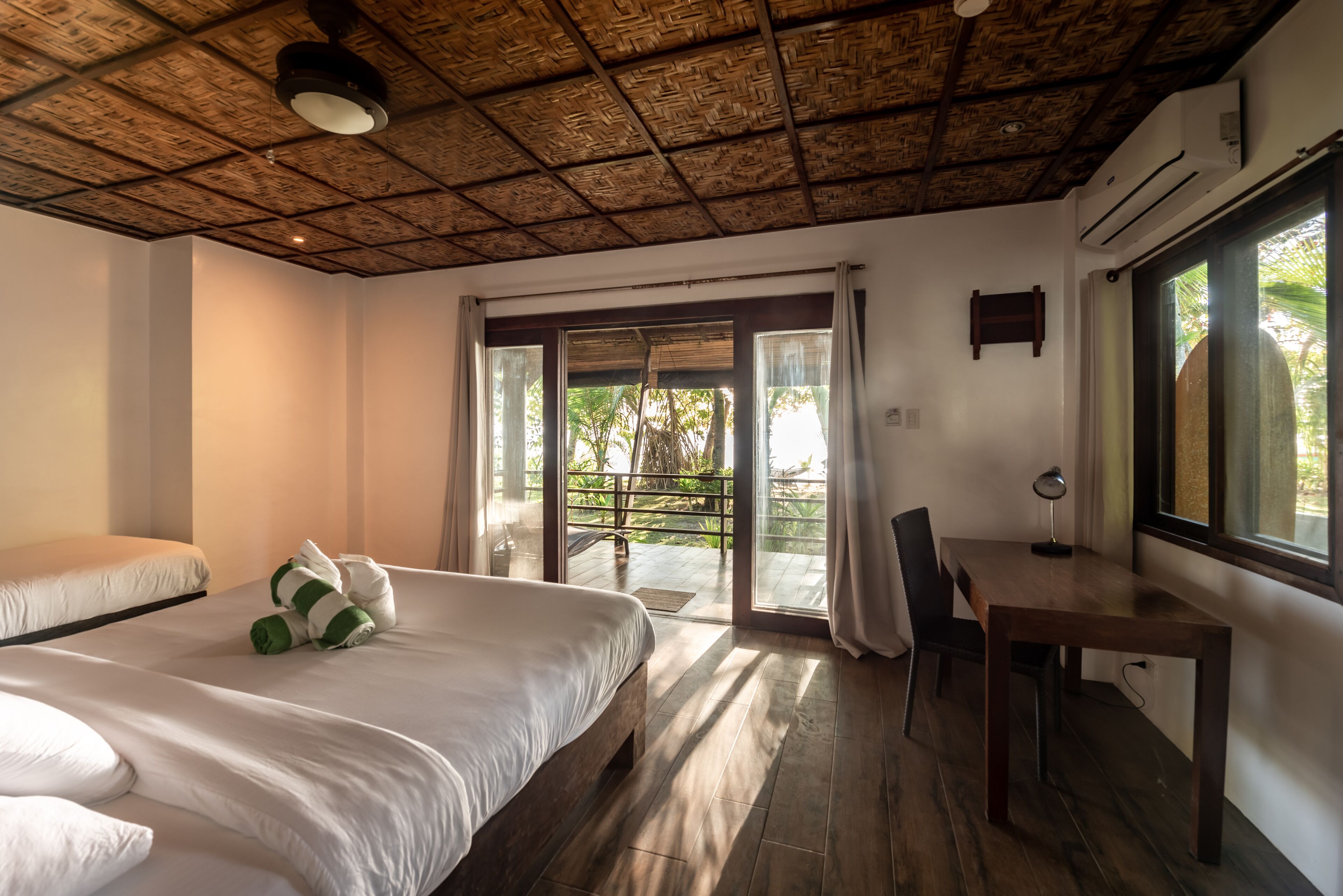 A bedroom with a bed, a desk, and a balcony.