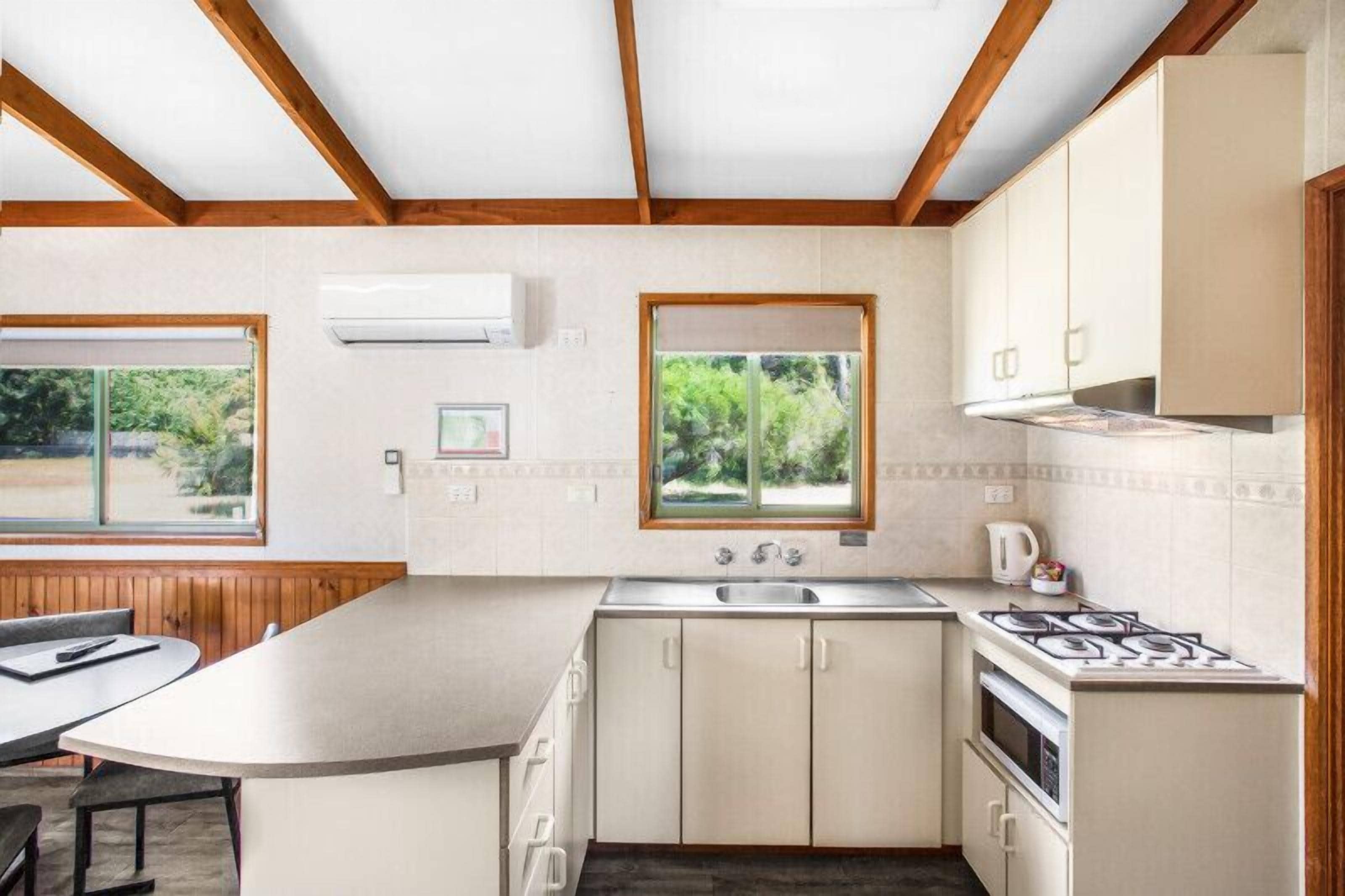 Una cocina moderna con una isla grande, horno empotrado y ventana con vistas a la vegetación.