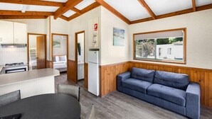 A compact kitchen with a dining area, a blue sofa, and wooden beams on the ceiling. - Discovery Parks - Grampians (Halls Gap)