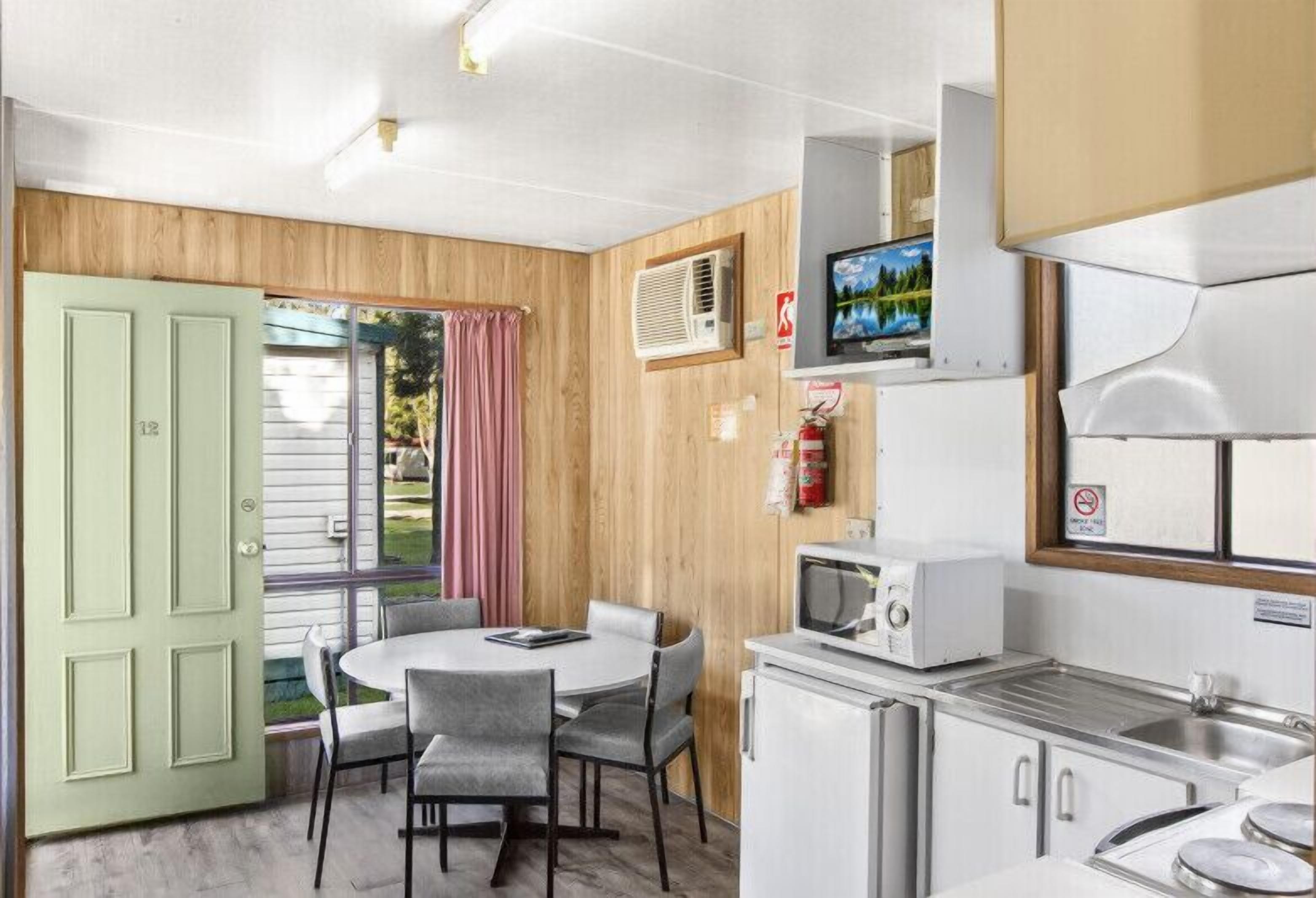 A compact kitchen with a dining area, a television, and a refrigerator.