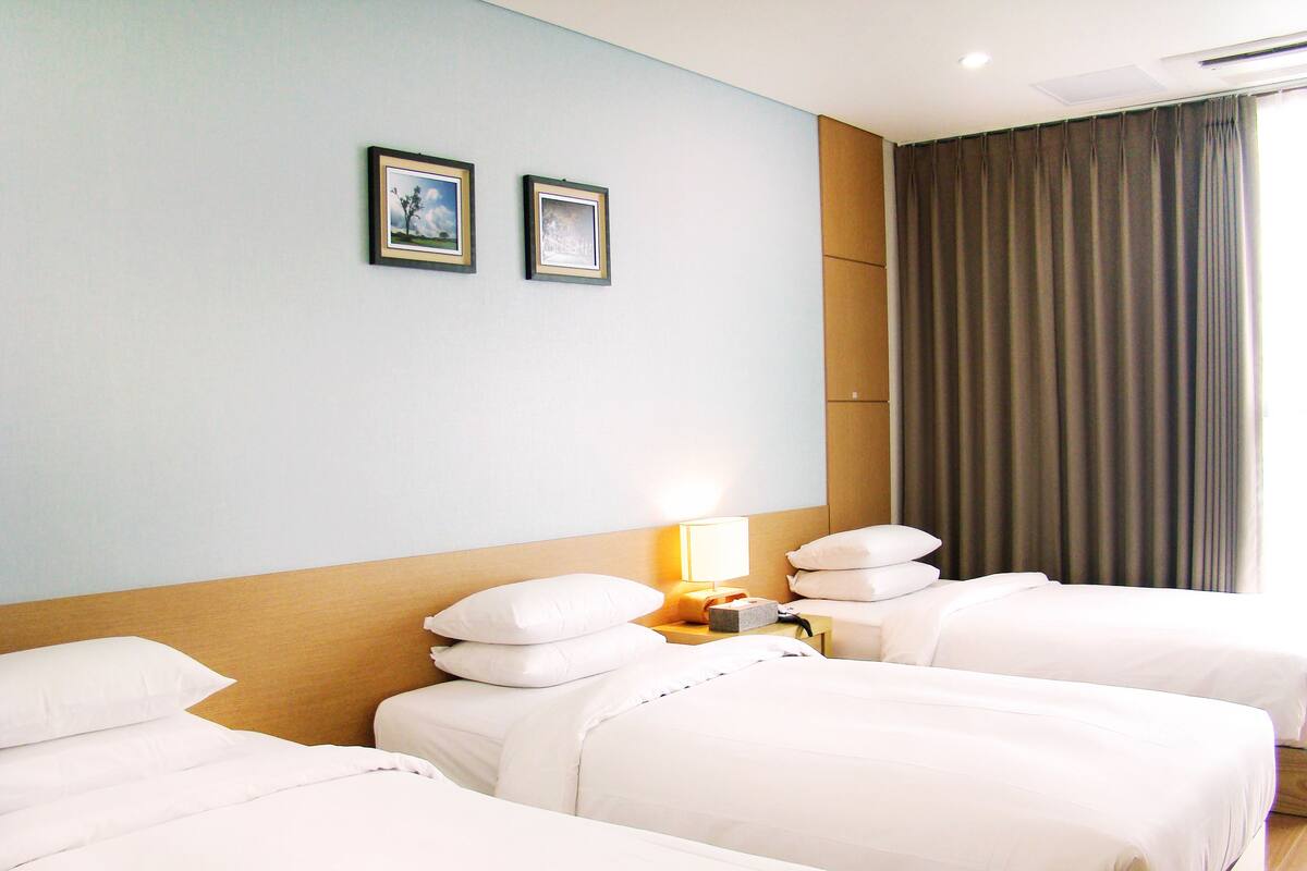 A hotel room with two beds, a nightstand with a lamp, and two framed pictures on the wall.