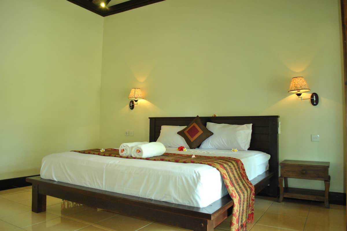 A neatly made bed with white linens and a colorful blanket, two wall-mounted lamps, and a small wooden nightstand.