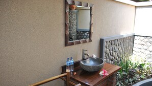 A bathroom with a stone sink, a mirror, and a wooden handrail. - Van Karning Bungalow (Pemuteran)