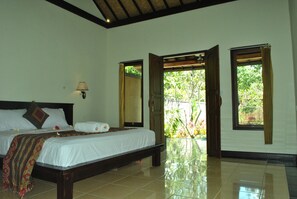 A bedroom with a bed, a nightstand, a lamp, and a window with curtains. - Van Karning Bungalow (Pemuteran)