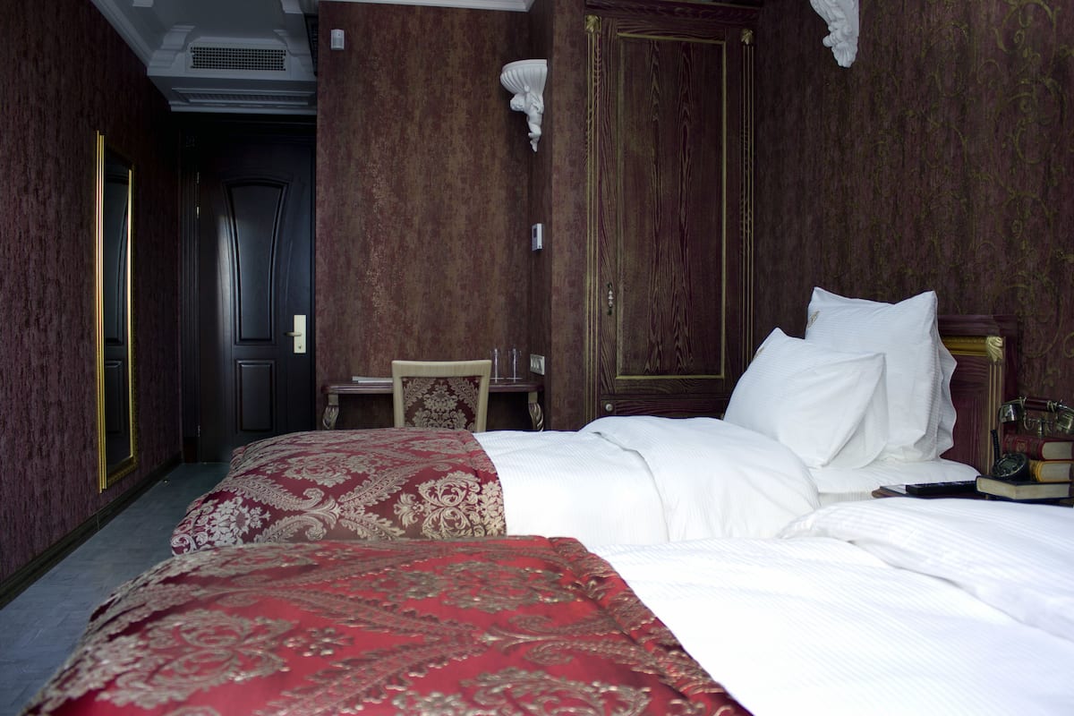 A hotel room with a large bed, a small table, and a wardrobe.