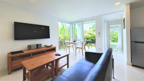 A modern living room with a flat-screen TV, wooden furniture, a sofa, and a dining area with a table and chairs. - Horizon Residence Rentals (Koh Samui)