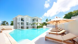A modern pool area with a clear blue pool, lounge chairs, and a large umbrella. - Horizon Residence Rentals (Koh Samui)