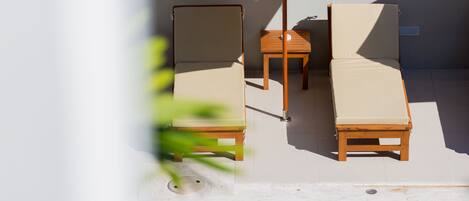 A poolside area with two lounge chairs and a table under a large umbrella.