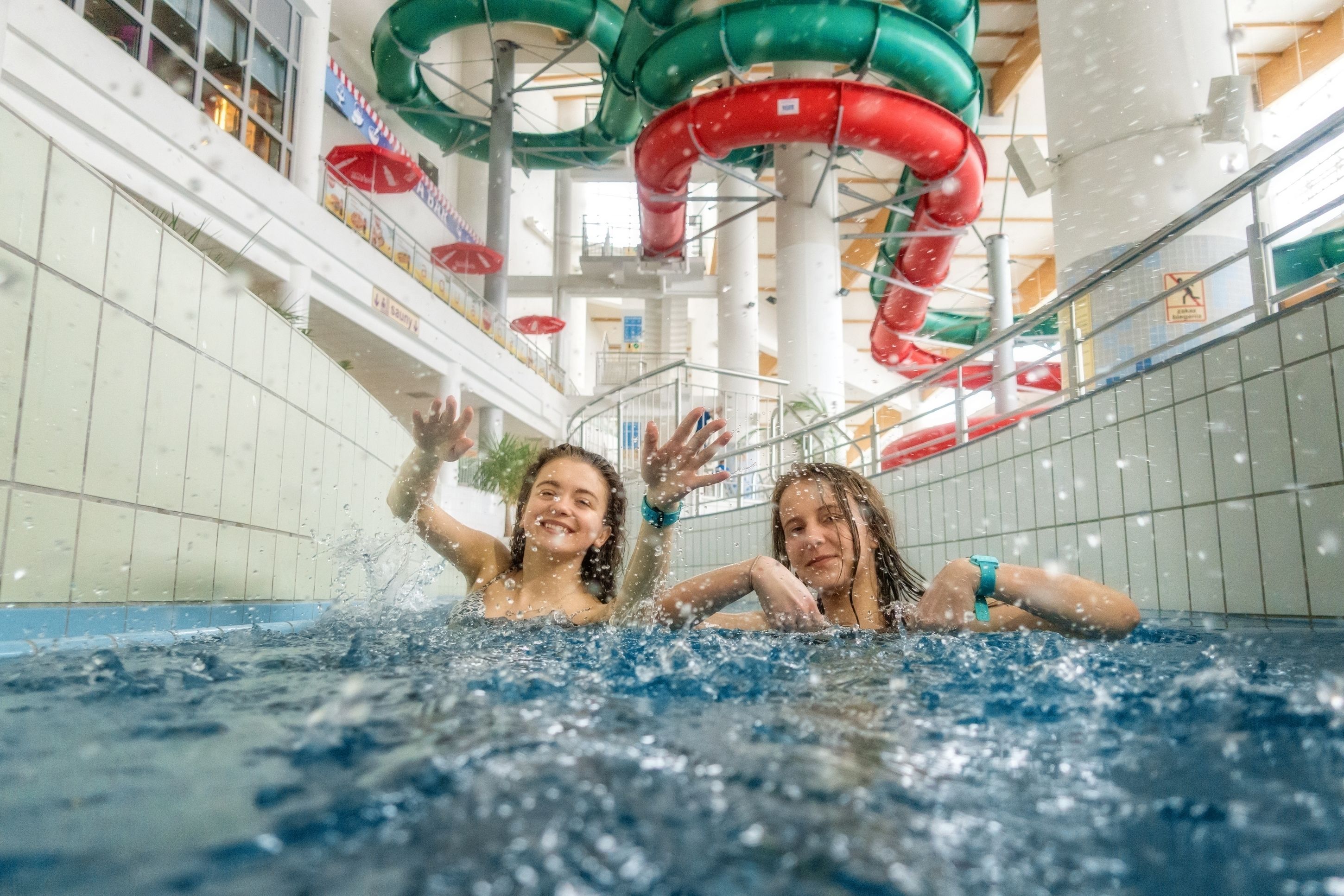 An indoor swimming pool with multiple slides and a tiled wall.