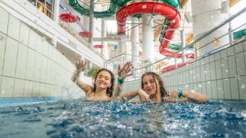 An indoor swimming pool with multiple slides and a tiled wall.
