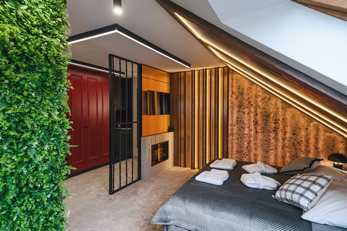 Un dormitorio moderno con cama, toallas y una pared verde.