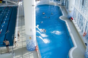 Una piscina interior con varias pistas, un trampolín y boyas salvavidas.