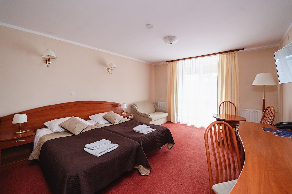 Una habitación de hotel con dos camas, un escritorio, una silla y un televisor.
