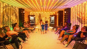 Una habitación con varias sillas reclinables dispuestas en semicírculo, una zona central con un niño y paredes decoradas con tiras de luz verticales.