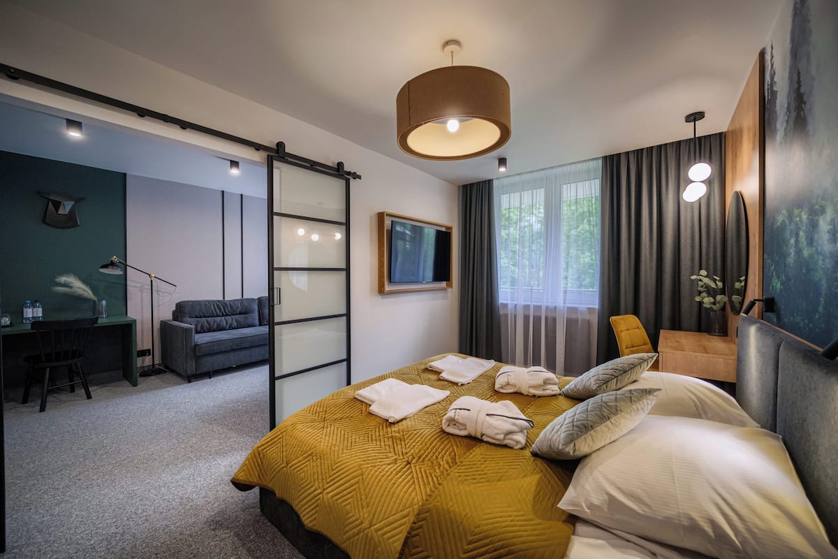 Una habitación de hotel moderna con una cama grande, un escritorio, una silla y una puerta corredera que da a un balcón.