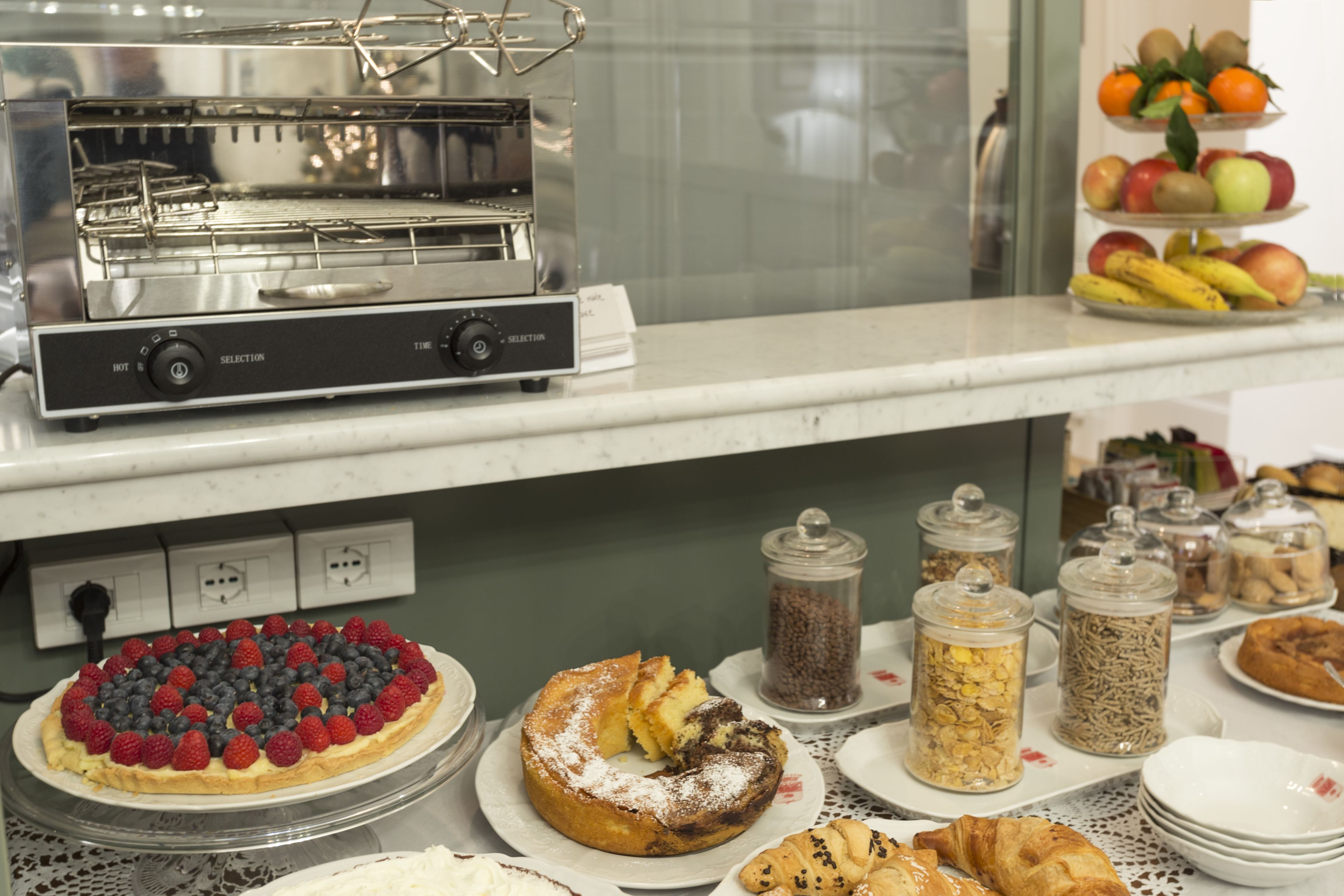 A buffet with various food items, including a pie with berries, a cake, and several pastries.