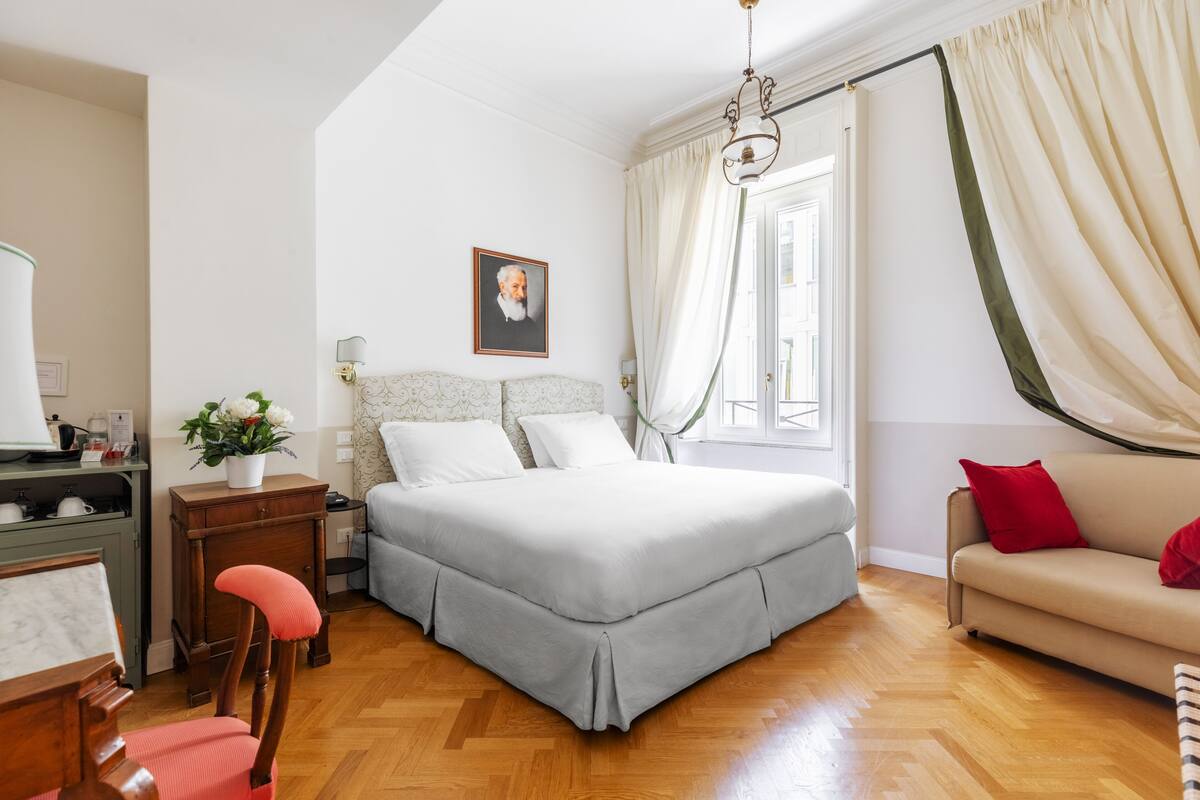 A bedroom with a bed, a sofa, a desk, and a chair.