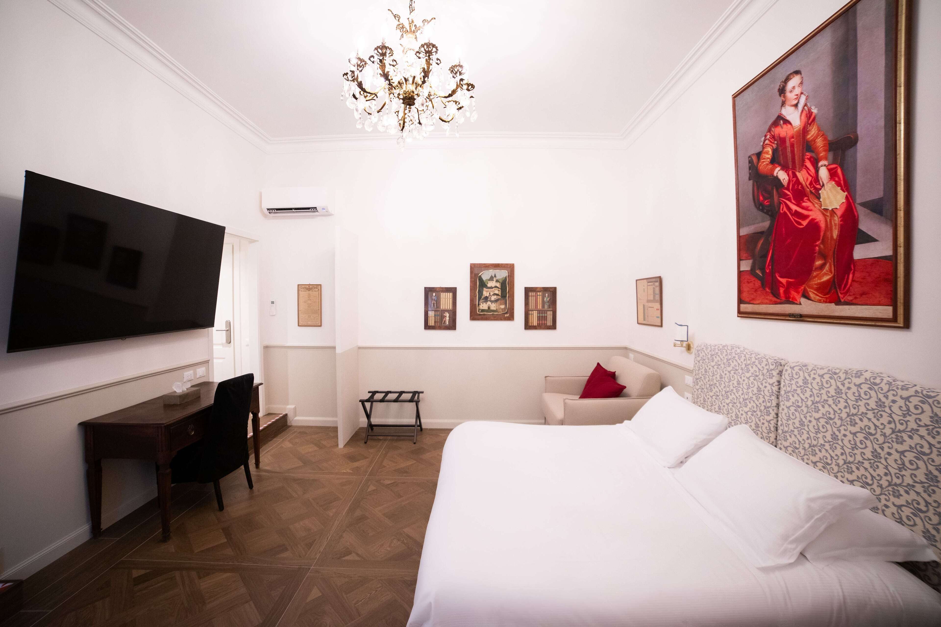 Ein Hotelzimmer mit einem großen Bett, einem Schreibtisch, einem Fernseher und einer Kandelaber.