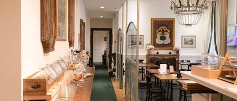 A long dining table with glassware and plates, flanked by wooden crates and a green carpet.