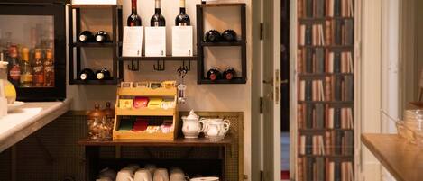 Un café con estanterías llenas de botellas de vino, una pizarra de menú y una estantería al fondo.