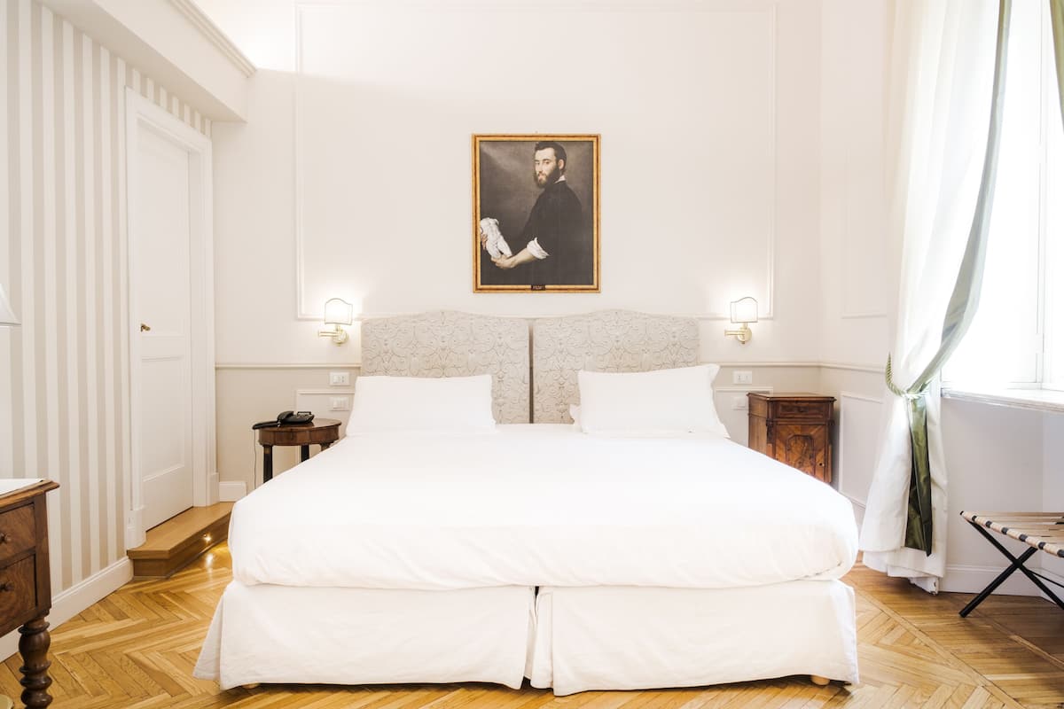 A large bed with a headboard, two bedside tables, and a wall-mounted picture.