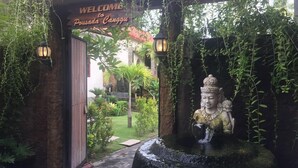 A welcoming entrance with a wooden archway and a Buddha statue in a water feature. - Pousada Canggu (Canggu)