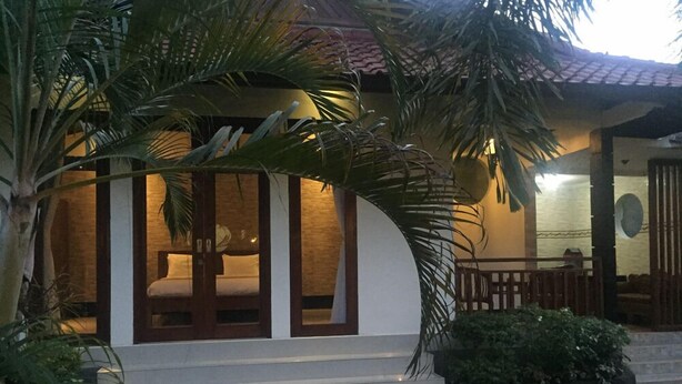 A traditional-style building with a wooden staircase leading to a door, surrounded by lush greenery. - Pousada Canggu (Canggu)