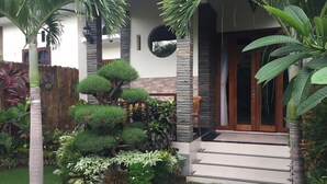 A well-maintained garden with a variety of plants, a small staircase leading to a wooden door, and a stone wall. - Pousada Canggu (Canggu)