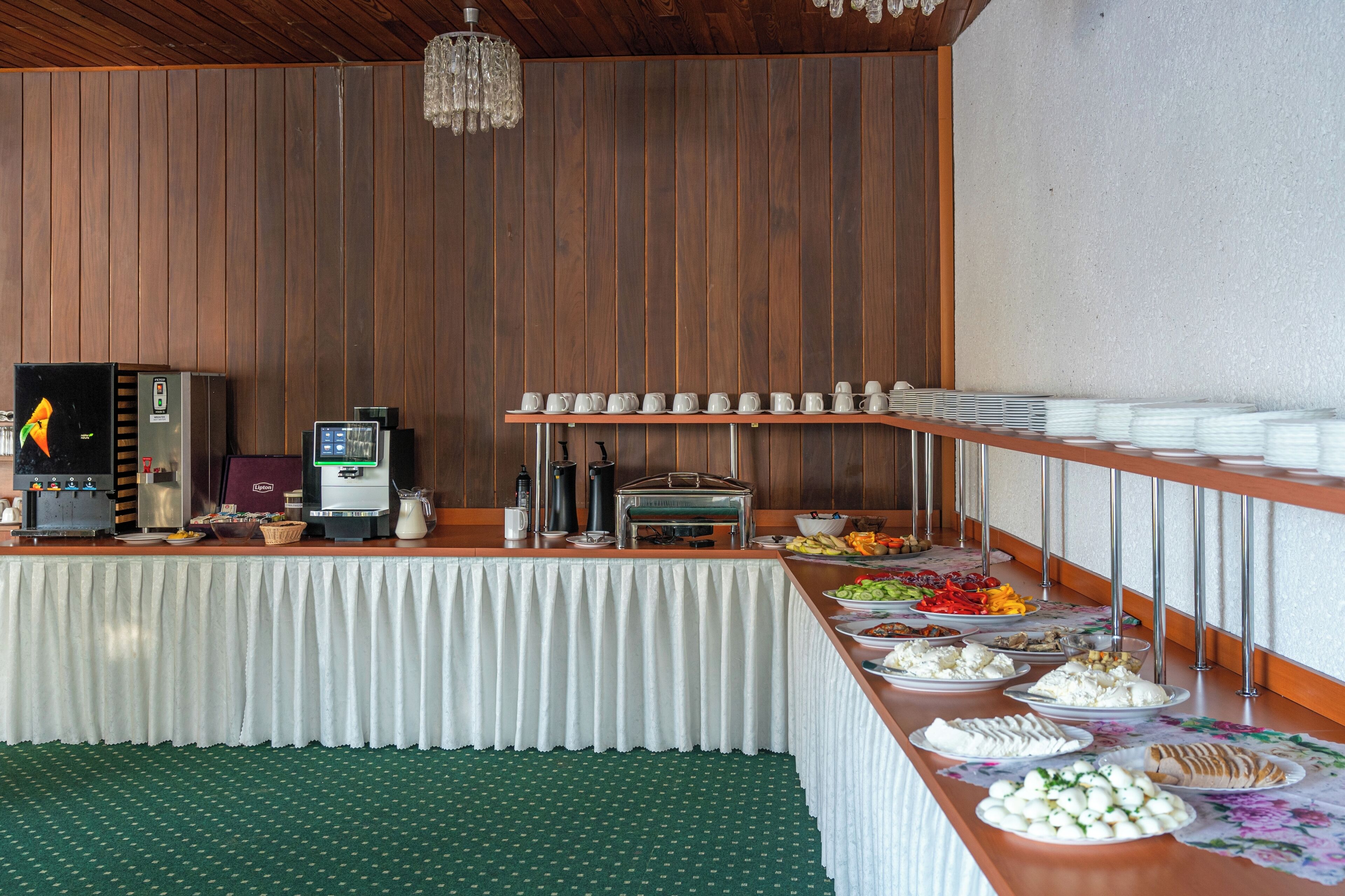 A buffet setup with various food items, a coffee machine, and a beverage dispenser.