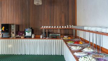 A buffet setup with various food items, a coffee machine, and a beverage dispenser.