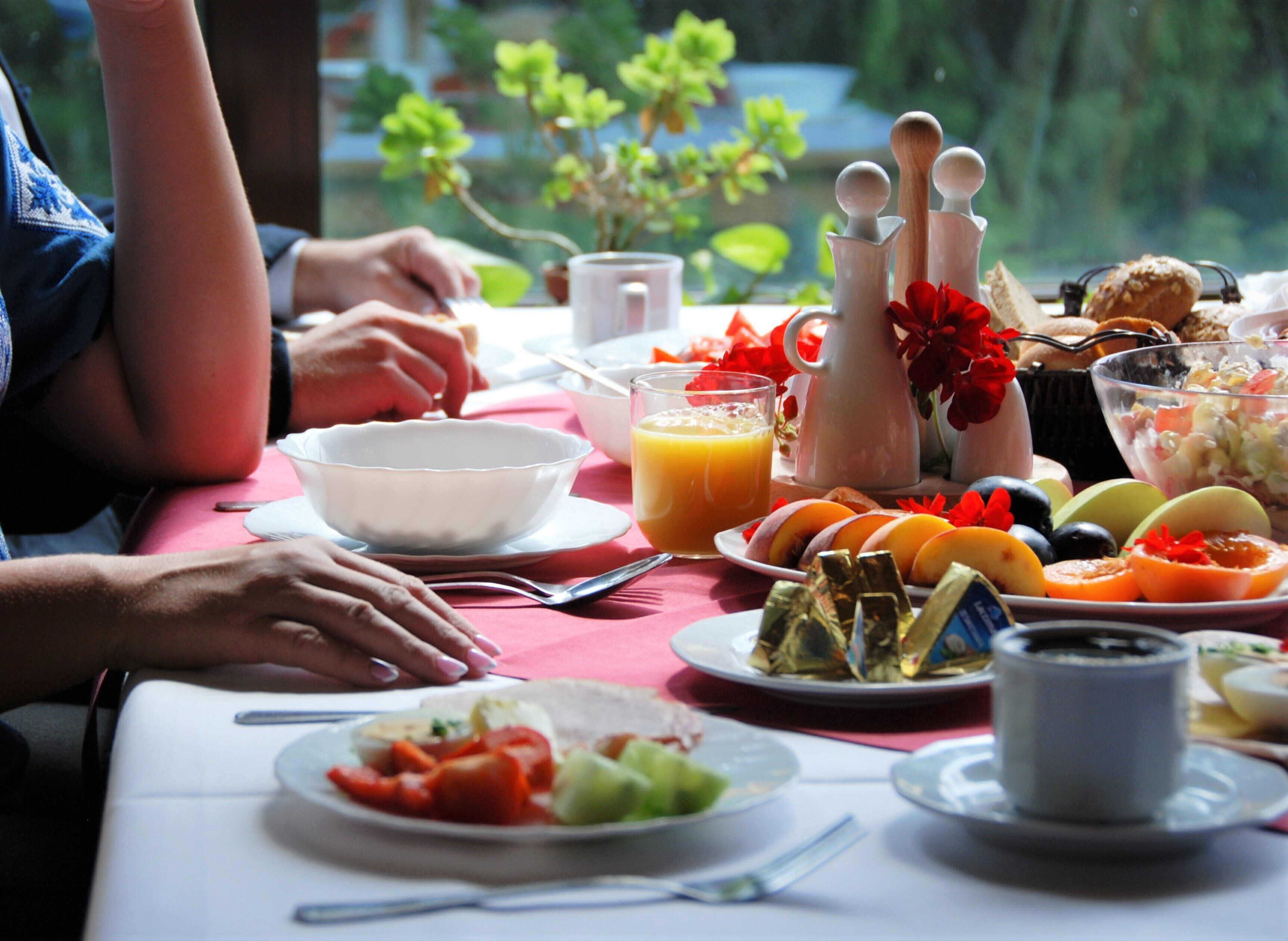 A dining table with various dishes, including fruits, vegetables, and a pitcher.