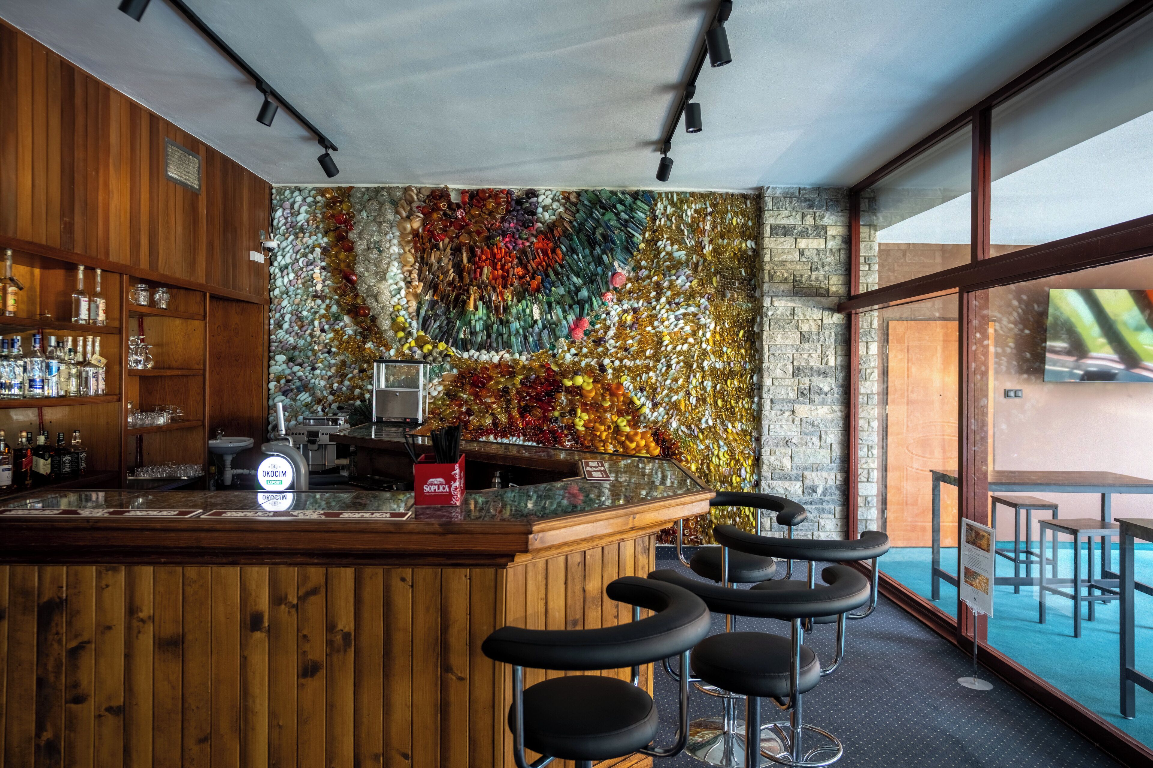 Een bar met houten kasten, een bar en een kleurrijke mozaïekwand.