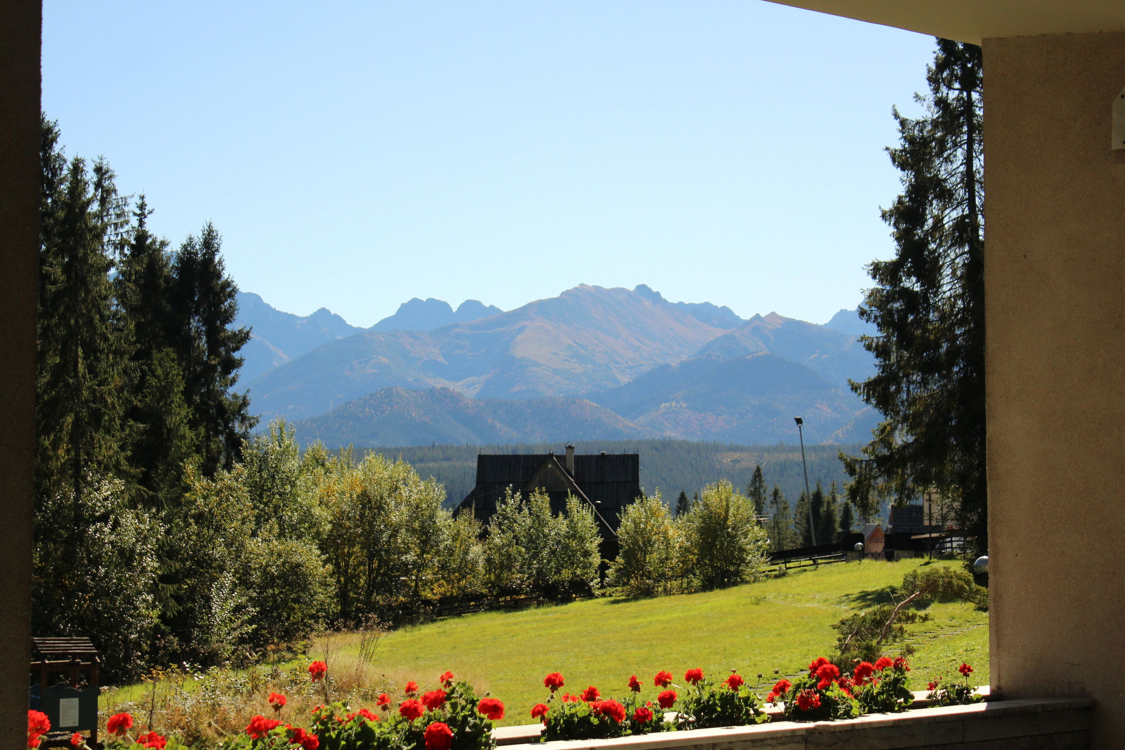 A view of a mountain landscape with a house in the foreground and a clear sky.