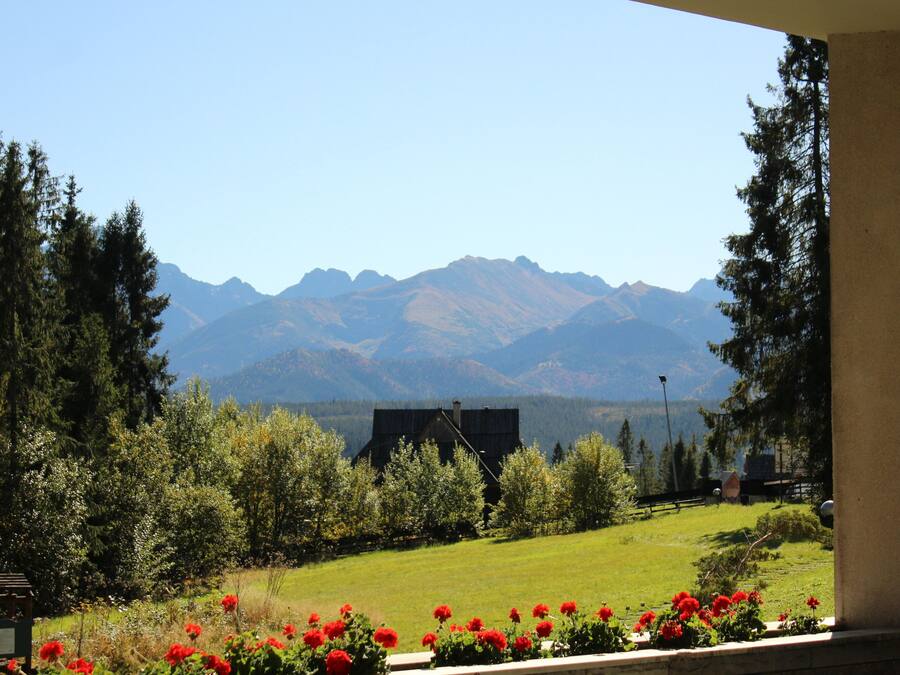 Vista de un paisaje montañoso con una casa en primer plano y un cielo despejado.