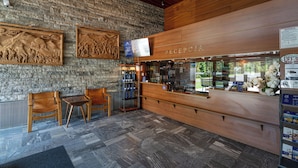 Un espace d’accueil avec un mur en pierre, un comptoir d’accueil en bois et des sièges.