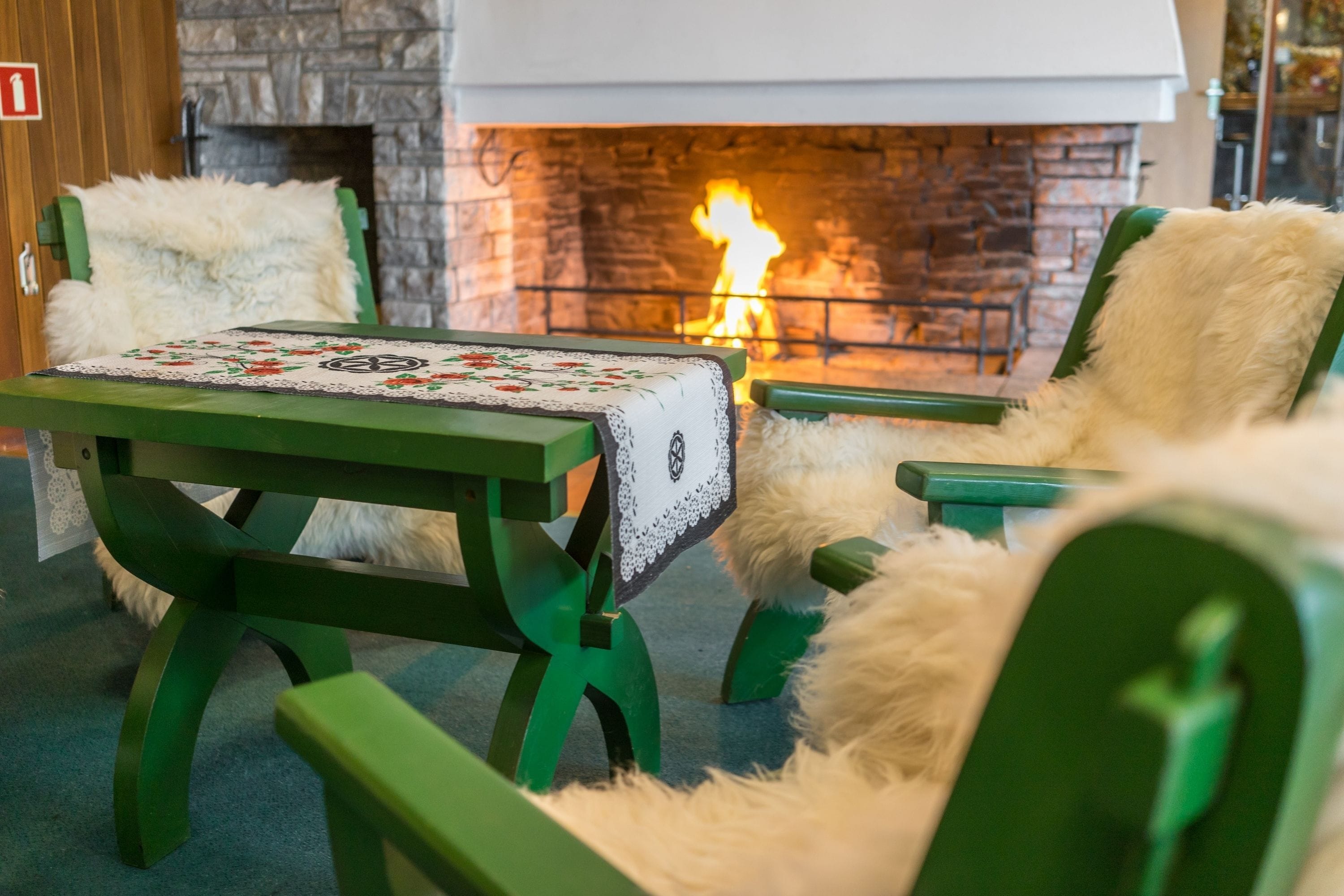 A cozy seating area with a table and chairs, a fireplace, and a stone wall.