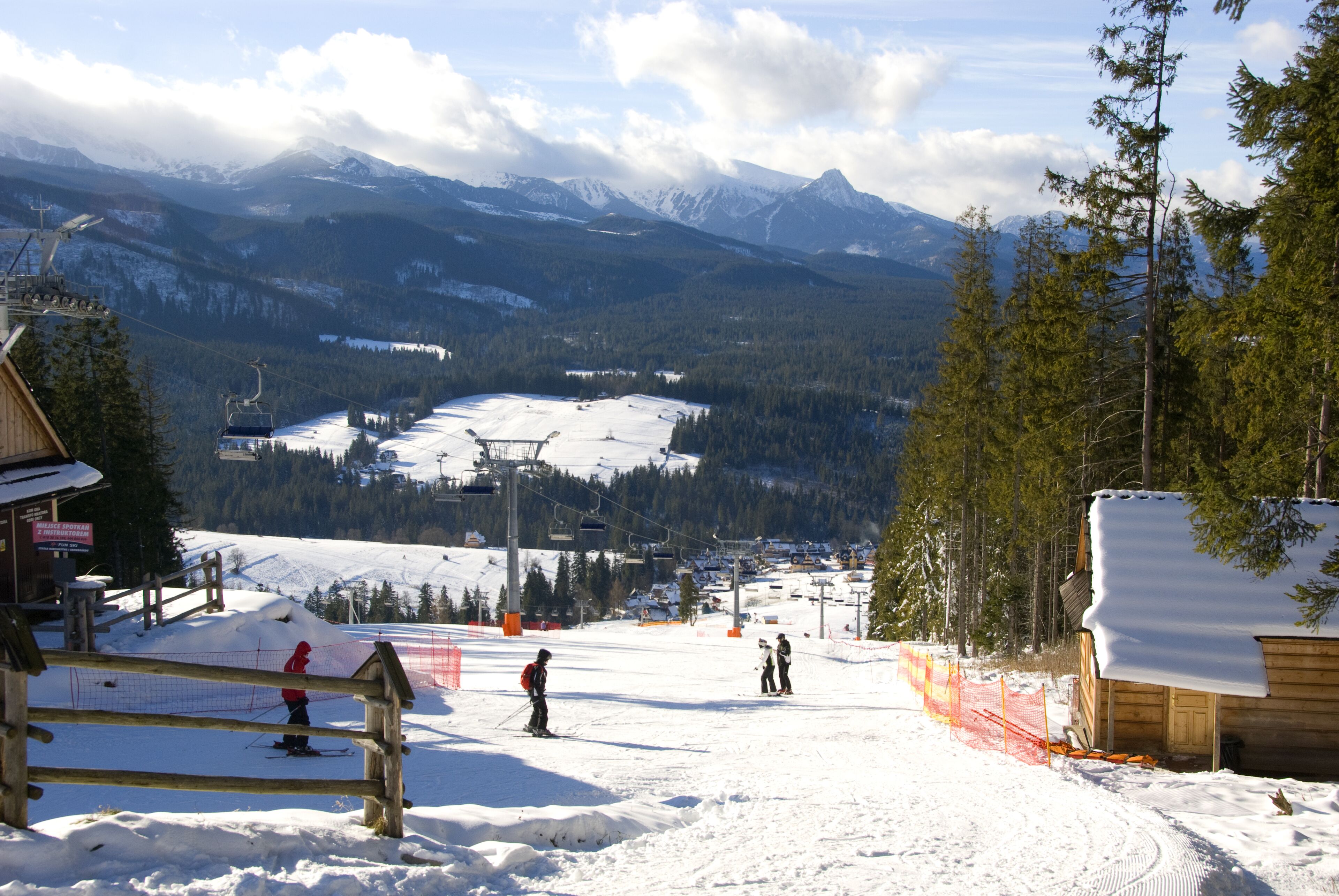 A ski resort with a chairlift, snow-covered slopes, and a wooden cabin.