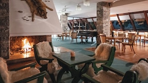 Un salon confortable avec une cheminée, des fauteuils moelleux et un grand panneau mural présentant des animaux empaillés.