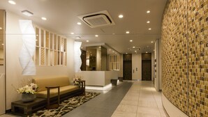 A modern hotel lobby with a reception desk, seating area, and decorative wall tiles.