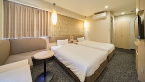 A hotel room with two beds, a sofa, a small round table, and a television.