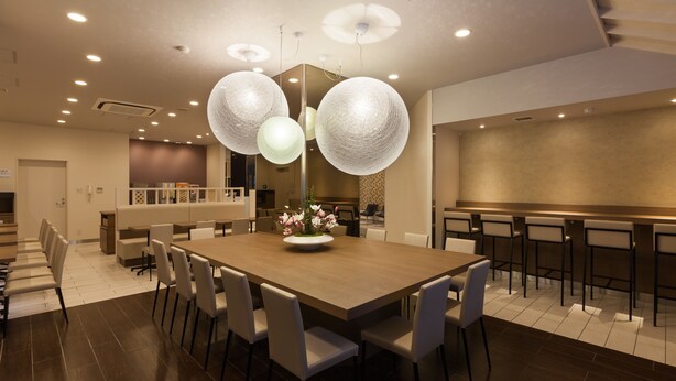 A modern dining area with a large wooden table, white chairs, and a central floral arrangement.
