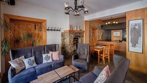 Una acogedora sala de estar con chimenea de piedra, muebles de madera y una lámpara moderna.