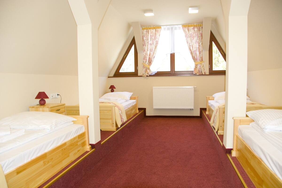 A bedroom with two wooden beds, a radiator, and a window with curtains.