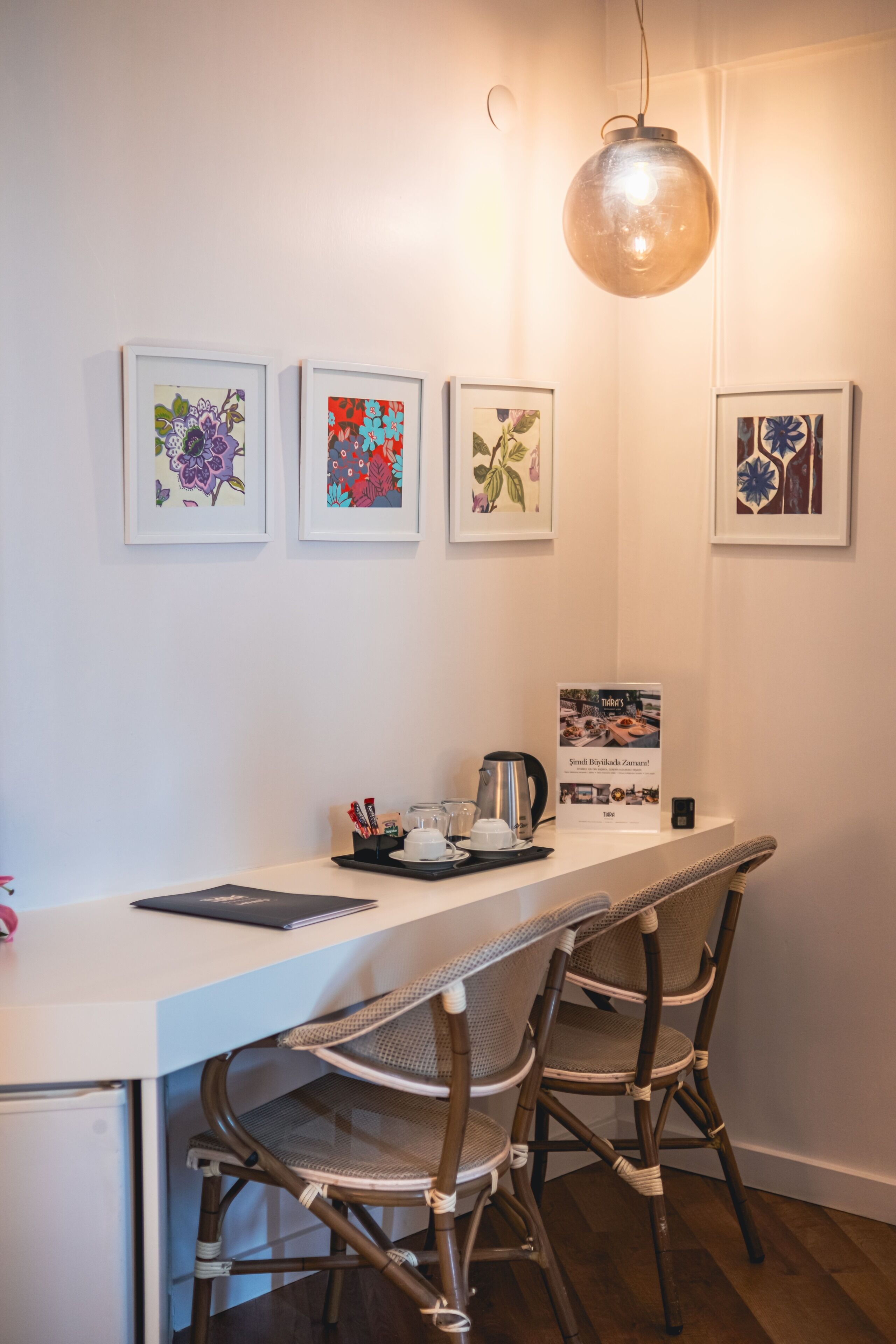 A dining area with a white table, wicker chairs, and framed artwork on the wall.