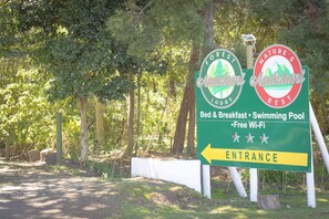 A sign for Andeloni Lodge with amenities including bed & breakfast, a swimming pool, and free Wi-Fi.